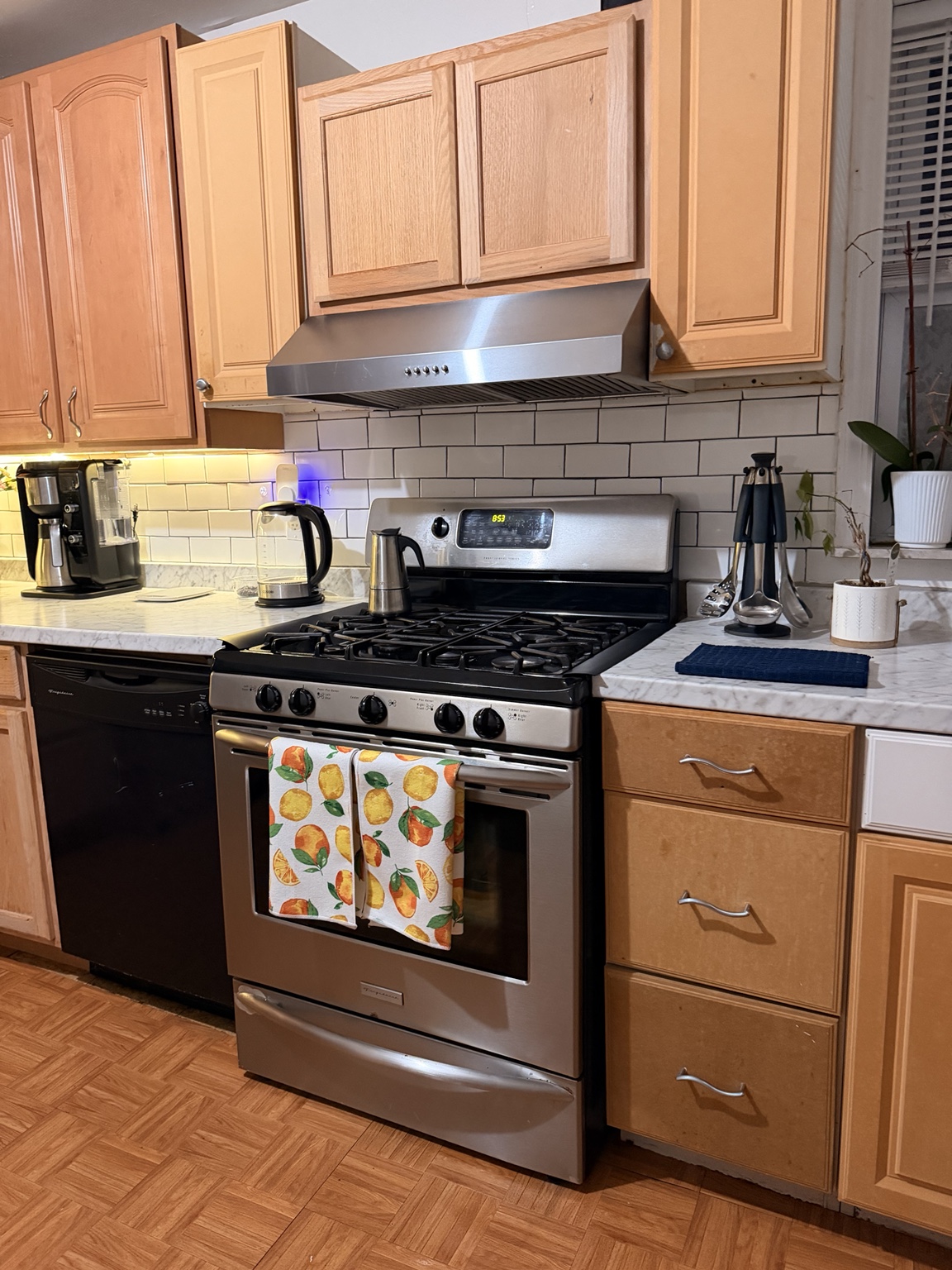 Clean stove and kitchen work surfaces in a home with light wood cabinetry